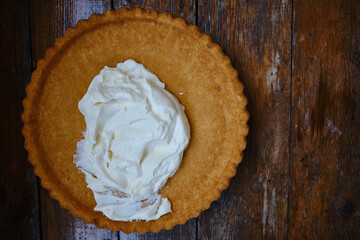 Delicious biscuit and creamy whipped cream on a wooden background. Freshly baked dessert for tea or a holiday. Sweet heart of whipped cream