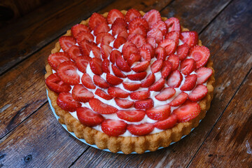 Delicious strawberry tart on a wooden background. Sweet pastry with fresh berries. Sweet dessert for tea and for the holiday
