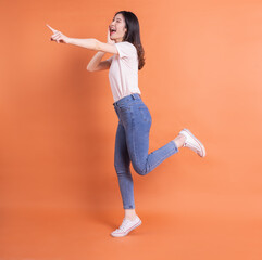 Full length image of young Asian woman posing on orange background