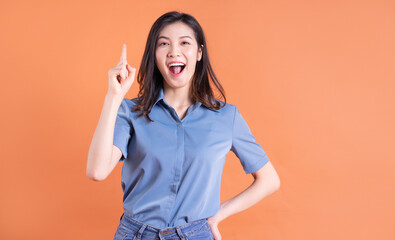 Young Asian business woman posing on orange background