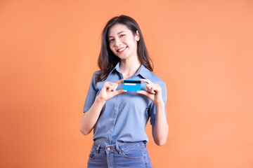 Naklejka premium Young Asian business woman posing on orange background