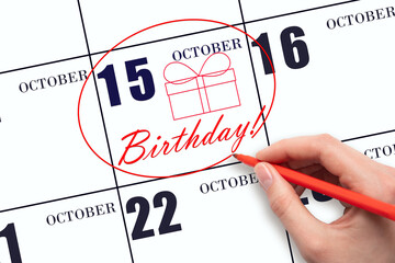 The hand circles the date on the calendar 15 October, draws a gift box and writes the text Birthday. Holiday.
