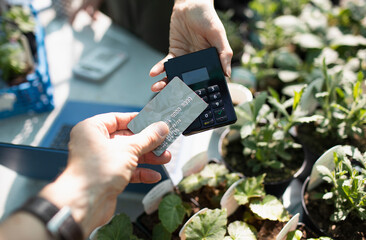 Close up customer paying for plants with smart card