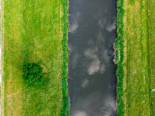 Fototapeta równoległe linie brzegowe kanału lub rzeki z trawnikiem i drzewem widziane z góry obraz