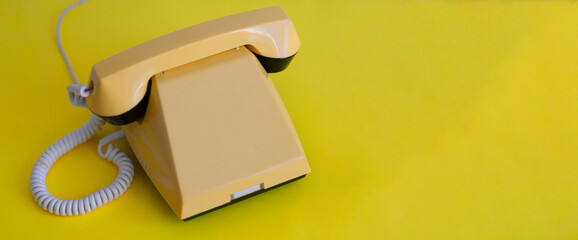 Yellow retro phone on a yellow background. Banner with space for text