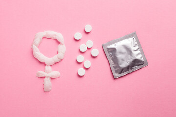 Woman venus symbol, contraceptive pills and condom on pink background. Safe sex and birth control...