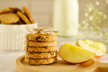 Oatmeal cookies with oats, apple, nuts and wholemeal flour free on an wooden background. A stack of oatmeal cookies tied with string on side view. Side view, copy space for text. Healthy food. 
