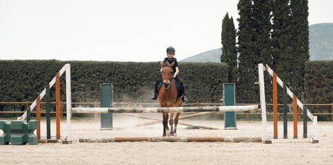 Young happy boy ridding horse during horseback lessons.