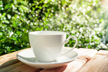 white ceramic coffee mug On the wooden floor, green tree bokeh background in the morning sun in the garden. soft focus.shallow focus effect.