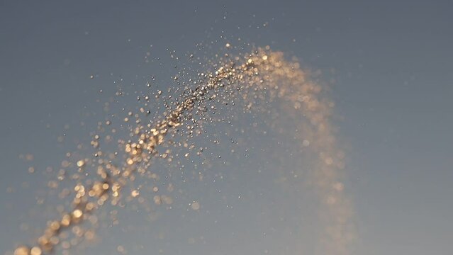 jet of water slow motion in the sunset rays of the sun