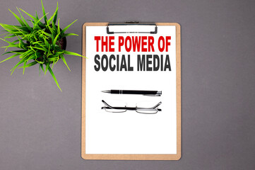 Text THE POWER OF SOCIAL MEDIA on the brown clipboard on the grey background. Business concept