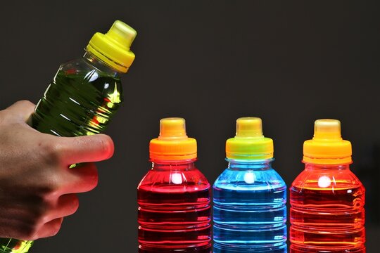 Hand Holding A Sports Drinks, Also Known As Electrolyte Drinks, Are Functional Beverages Whose Stated Purpose Is To Help Athletes Replace Water, Electrolytes, And Energy Before, During Sports Activity