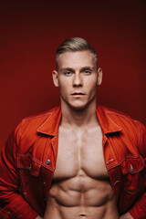 Close up portrait of handsome blond man in red jean jacket. Studio portrait of sexy young guy.