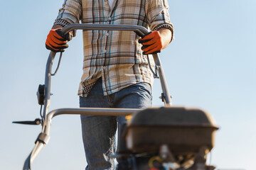 Man using aerator machine to scarification and aeration of lawn or meadow