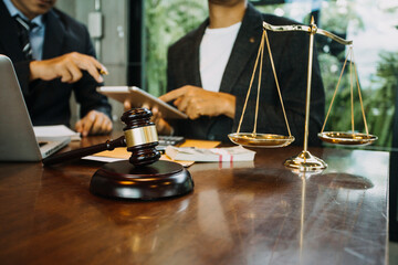 Justice and law concept.Male judge in a courtroom with the gavel, working with, computer and docking keyboard, eyeglasses, on table in morning light