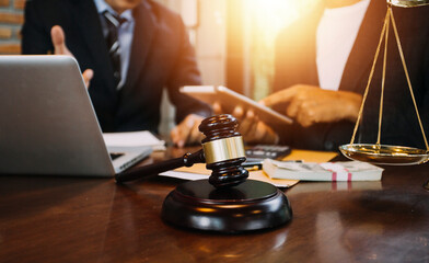 Justice and law concept.Male judge in a courtroom with the gavel, working with, computer and docking keyboard, eyeglasses, on table in morning light