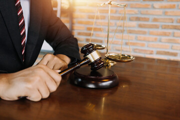 Obraz premium Justice and law concept.Male judge in a courtroom with the gavel, working with, computer and docking keyboard, eyeglasses, on table in morning light