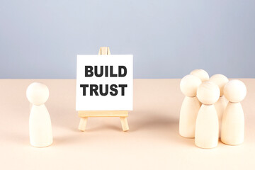BUILD TRUST text on a easel with wooden figure, meeting concept
