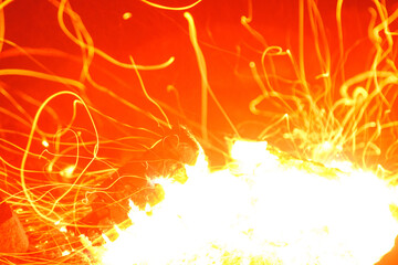 Closeup shot of campfire brightly burning at night throwing sparkles.