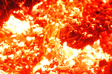 Closeup shot of campfire brightly burning at night throwing sparkles.