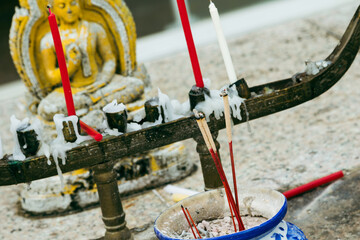 Closeup of buddhist altar, candles and praying Buddha statue .