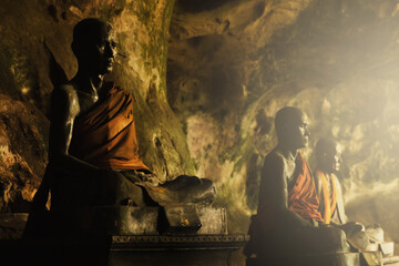 Closeup shot of metallic buddhist statues in cave in Thailand.