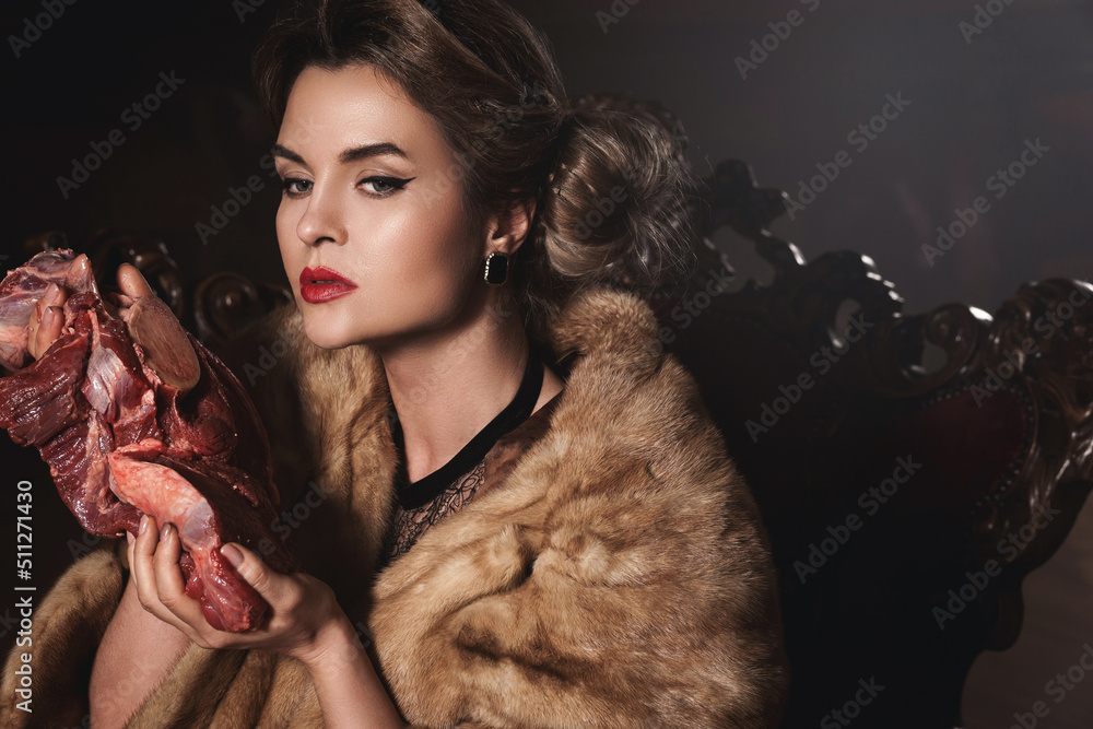 Wall mural provocative image of gorgeous wearing wearing fur coat and holding piece of raw beef. animal rights 