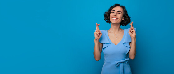 Gorgeous stylish and elegant woman is praying with crossed fingers for some wishes and looks...