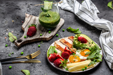 Fried egg, avocado, strawberry, grilled chicken fillet, cheese, nuts and arugula, Low carb high fat breakfast, Ketogenic diet. top view