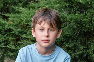 A 9-year-old boy looks intently into the camera. Portrait of a white Eastern European boy in nature