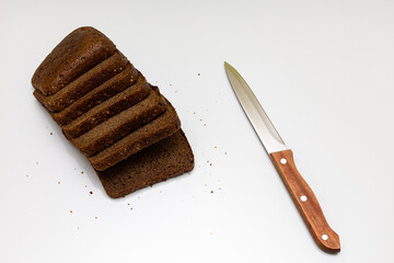 a cut piece of black bread next to which lies a knife