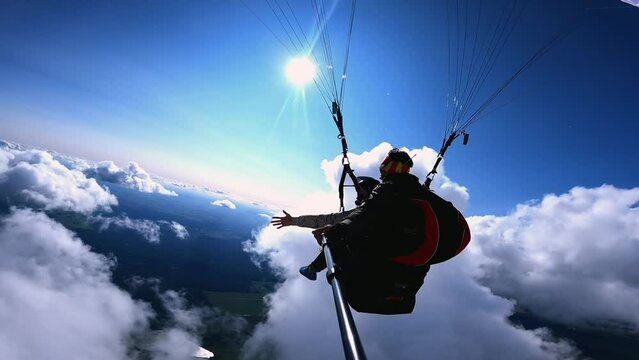 a guy and a girl are paragliding in the clouds in sunny weather