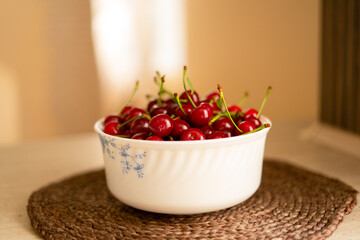 Close up of many ripe red cherries in a white bowl.