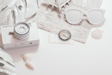 Traveler white accessories on white background with retro camera, sunglasses, seashells, airbus and tropical palm leaf. Flat lay minimal concept. Summer background.