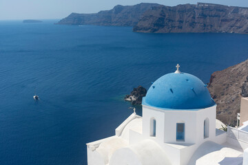 Fototapeta na wymiar Santorini blue dome of white church in Oia with sea view and volcano, Greece landmark