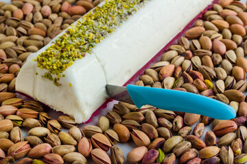 Sliced Traditional Turkish ice cream Maras with a blue knife on shelled pistachio nuts