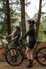 Fototapeta na wymiar Female cyclists standing holding their bikes in the middle of the forest. Selective focus