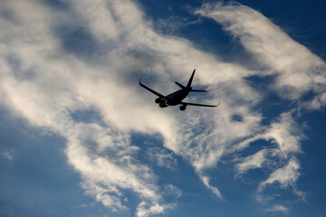 Naklejka na ściany i meble Airplane in the cloudy sky.