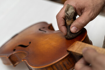 Close-up of unrecognizable Latin American Luthier varnishes a violin the old fashioned way using...