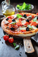 Delicious and fresh pizza Capricciosa with mozzarella, tomatoes and prosciutto.