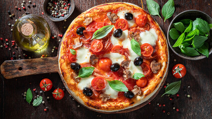Tasty and healthy pizza Capricciosa with mozzarella, tomatoes and prosciutto.
