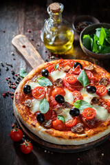 Delicious pizza Capricciosa made of tomatoes, olives, cheese and ham.