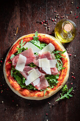 Delicious pizza Parma made of prosciutto ham, parmesan and arugula.