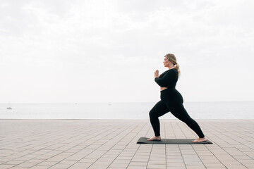 plus size girl practicing yoga in front of the ocean