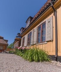 Façade of a yellow wood mansion building with dorms and flowers in a park a sunny summer day in Stockholm