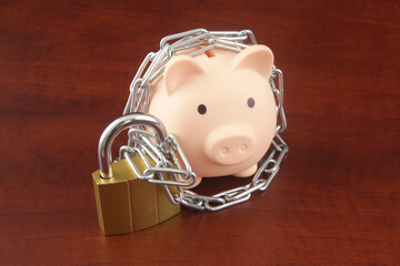 Piggy bank with padlock and chain on wooden background. Money safety, financial protection...
