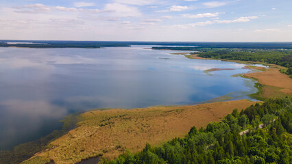Aerial view of lake with sky reflection. Blue lake and green forest. Image for design. Space for text.