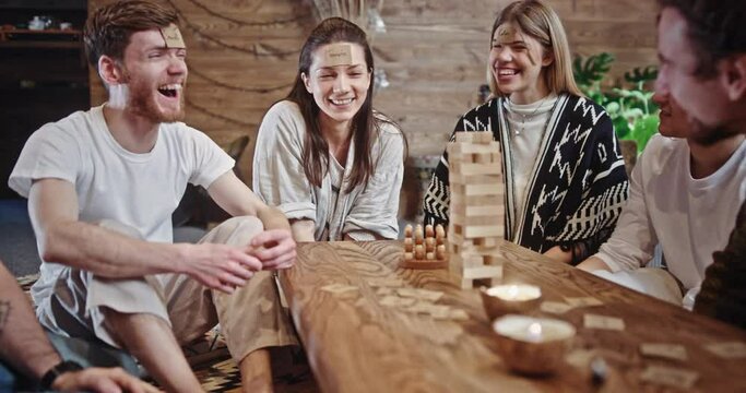 Cheerful friends play fun game stacking wooden details