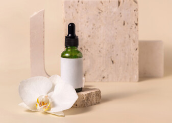 Fototapeta na wymiar Green glass dropper bottle near white orchid flower on light yellow, Mockup. Skincare product
