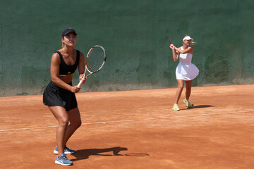 girls playing a tennis doubles match on a clay court
